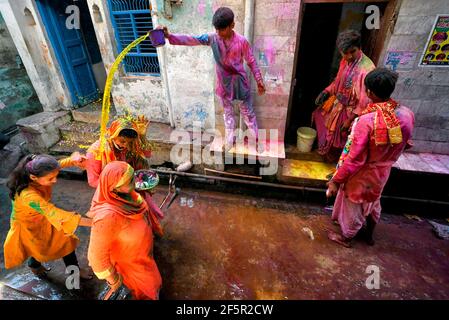 Mathura, India. 23rd Mar, 2021. A man seen pouring yellow liquid at a devotee during the Holi Festival.Holi Festival of India is one of the biggest colourful celebration in India as many Tourists and devotees gather to observe this colourful event. Marking the beginning of spring, the festival celebrates the divine love of Radha and Krishna and represents the victory of good over evil. (Photo by Avishek Das/SOPA Images/Sipa USA) Credit: Sipa USA/Alamy Live News Stock Photo