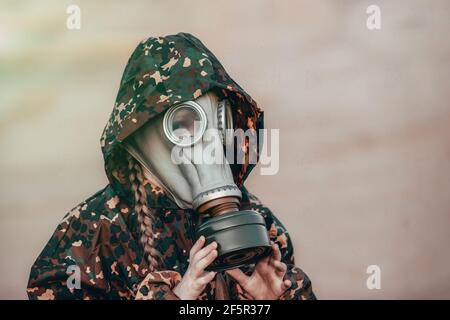 Little kid girl in gas mask in sand desert after apocalypse. Lonely child in respirator. Eco concept about pollution and toxic air. Stock Photo