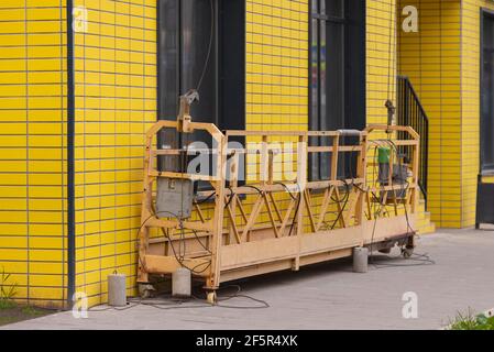Cradle for lifting workers. Empty bassinet on the ground floor before going up to the roof. Stock Photo