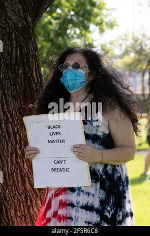 Middle Age White woman wearing a mask and holding a sign at a black lives matter protest Stock Photo