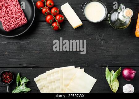 Empty space clean Frame set The concept of cooking lasagna. Italian Ingredients, lasagna sheets meat herbs tomatoes, bechamel sauce, on black wooden t Stock Photo