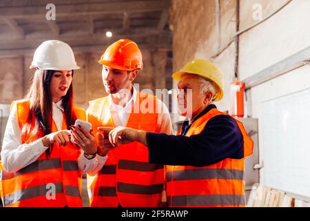 Group of engineers and workers discuss production plans Stock Photo