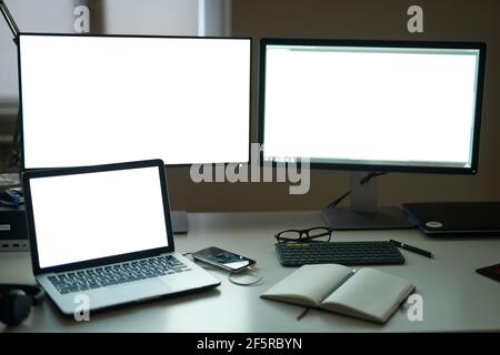 Many blank white screen of computer monitors with accessories and work tools on modern freelance working space Stock Photo