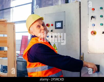 the senior man in uniform is working at the factory Stock Photo