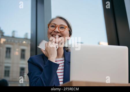 Portrait of mature asian businesswoman working online, planning project, using laptop computer Stock Photo