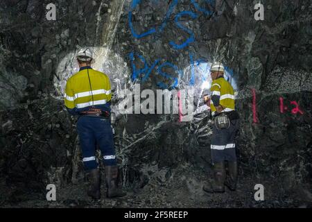 Geologist sampling ore and marking drilling instructions in underground mine shaft. Western Australia Stock Photo