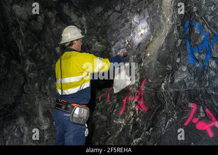 Geologist sampling ore and marking drilling instructions in underground mine shaft. Western Australia Stock Photo