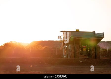 Dump trucks at sunset on mining Go Line in open pit mining area. Stock Photo
