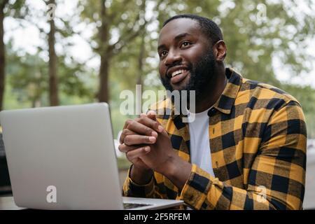 Portrait of young African American using laptop computer. Smiling freelancer working, planning project, sitting at workplace