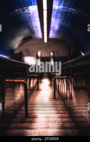 A long narrow iron stairway stretching deep underground to a metro station platform as an auxiliary way in between two escalators, shallow depth of fi Stock Photo