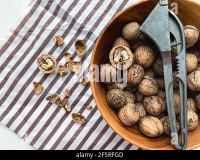 Wooden bowl of walnuts with nutcracker on a striped background. Stock Photo