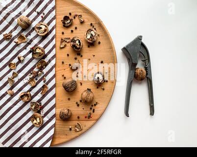 Cracked walnuts on a wooden board and white background with nutcracker Stock Photo