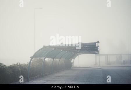 View of an empty foggy covered car parking on a territory of a typical gas station zone of Portugal; a parking lot with an overhang on a grey misty mo Stock Photo