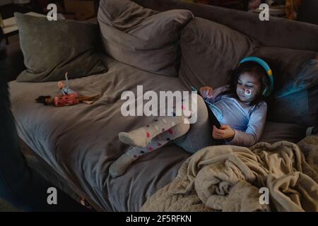 Multiracial girl using digital tablet on couch Stock Photo
