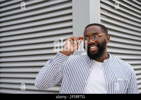 Portrait of confident smiling African man wearing stylish eyeglasses isolated on grey background Stock Photo