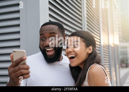 Emotional African American couple using smartphone shopping online, focus on man face Stock Photo