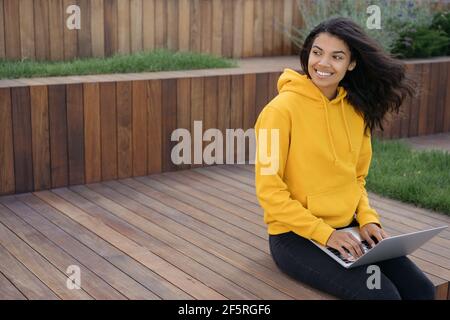 Beautiful African American woman using laptop computer, working freelance project, looking away, copy. Successful student studying, online education Stock Photo
