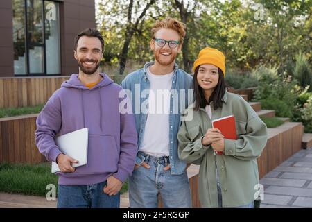 Group of smiling multiracial university student standing together, looking at camera, smiling. Portrait of happy successful team of young developers Stock Photo