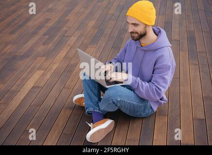 Handsome bearded man using laptop, working from home. Portrait of young successful programmer sitting at workplace. Student studying, online education Stock Photo