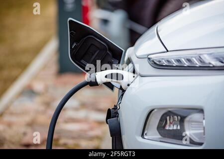 Selective focus shot of an electric car at a charging station with the power cable plugged in Stock Photo