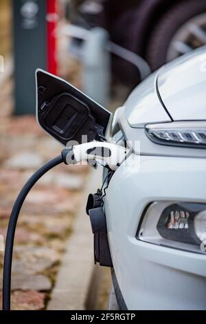 Selective focus shot of an electric car at a charging station with the power cable plugged in Stock Photo