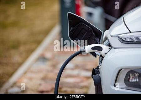 Selective focus shot of an electric car at a charging station with the power cable plugged in Stock Photo