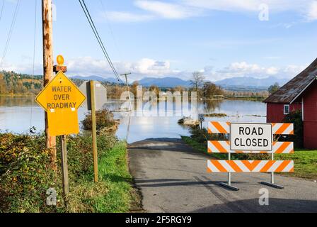 Multiple signs warning of flooding on country road in the Snoqualmie valley of Washington State when the Snoqualmie River flooded Stock Photo