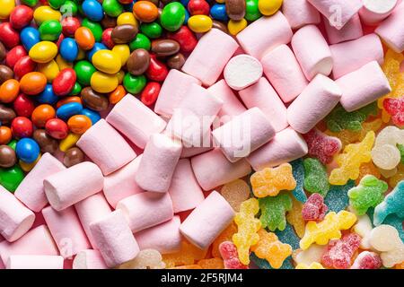 close-up of colored animal jelly beans colored chocolate balls and pink marshmallows placed in three diagonal lines occupying the entire image Stock Photo