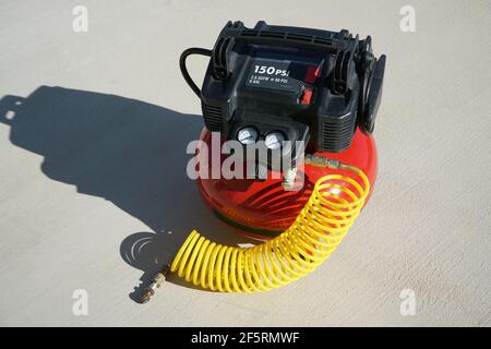 Portable electric air compressor with coiled hose. Stock Photo
