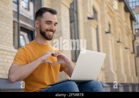 Successful influencer using laptop computer communication online with subscribers. Handsome smiling man having video call Stock Photo