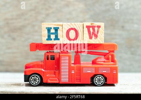 Fire ladder truck hold letter block in word how on wood background Stock Photo