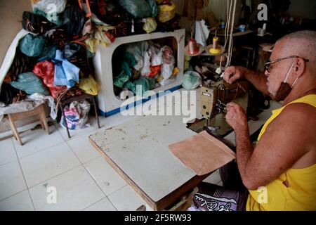 salvador, bahia, brazil - february 8, 2021: artisan sews with a machine in a piece of leather in a craft workshop in the Barroquinha region in the cit Stock Photo