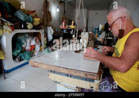 salvador, bahia, brazil - february 8, 2021: artisan sews with a machine in a piece of leather in a craft workshop in the Barroquinha region in the cit Stock Photo