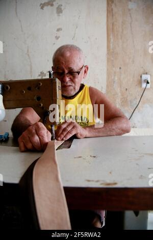 salvador, bahia, brazil - february 8, 2021: artisan sews with a machine in a piece of leather in a craft workshop in the Barroquinha region in the cit Stock Photo