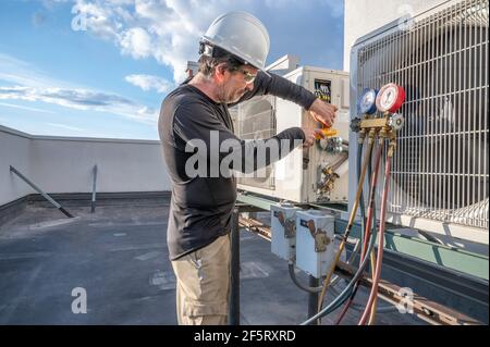 HVAC tech checking a mini split air conditioner amps with a meter Stock Photo
