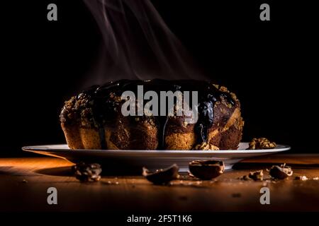 Smoky walnuts cake of chocolate sauce on the plate in low light. Stock Photo