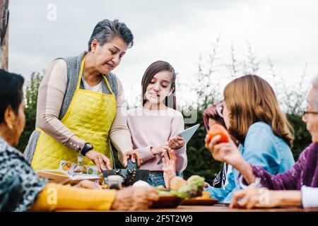 three generations of mexican women grandmother and daughter cooking spicy sauce at home in Mexico city Stock Photo