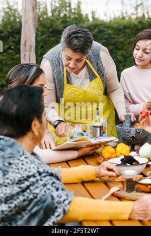 three generations of mexican women grandmother and daughter cooking spicy sauce at home in Mexico city Stock Photo