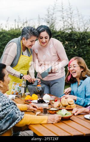 three generations of mexican women grandmother and daughter cooking spicy sauce at home in Mexico city Stock Photo