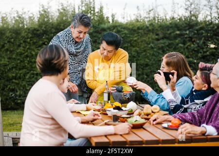 latin grandmother and granddaughter, daughter cooking mexican food at home, three generations of women in Mexico Stock Photo