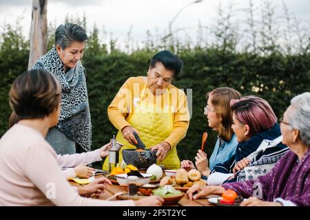 latin grandmother and granddaughter, daughter cooking mexican food at home, three generations of women in Mexico Stock Photo