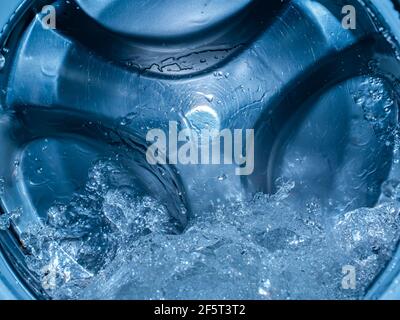 Rotating drum in the washing machine tub with water. Washer. Automatic laundry. Service and repair of equipment. Splashing water. Repair shop. Stainle Stock Photo