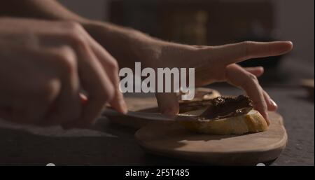 Man spreading chocolate hazelnut spread on baguette slices, wide photo Stock Photo