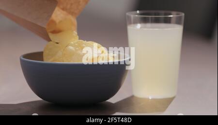 Man hand pour potato chips to blue bowl with ginger beer on background, wide photo Stock Photo