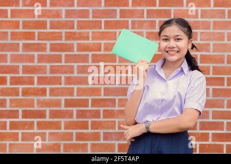 Asian girl teen student uniform happy smiling portrait with book for education back to school concept. Stock Photo