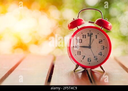 9 o'clock Classic Alarm Clock  on Wood Table with Sun Light green background. Stock Photo