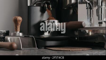 man grinding fresh coffe in single spout portafilter with professional grinder, wide photo Stock Photo