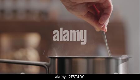 man hand stir fettuccine pasta in saucepan with boiling water closeup , wide photo Stock Photo