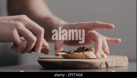 Man spreading chocolate hazelnut spread on baguette slices, wide photo Stock Photo