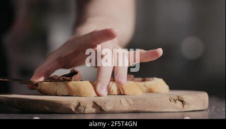 Man spreading chocolate hazelnut spread on baguette slices, wide photo Stock Photo